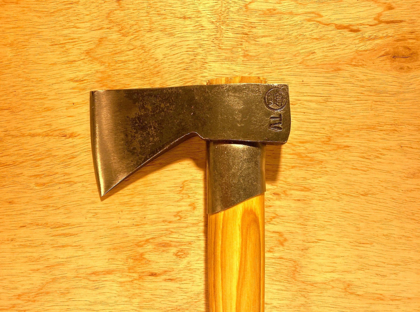 Close-up of the GRF Gransfors Bruk Outdoor Axe, featuring a wooden handle and metallic blade, placed on a light wooden surface—a tool preferred by survival expert Lars Fält from the Swedish Armed Forces Survival School.