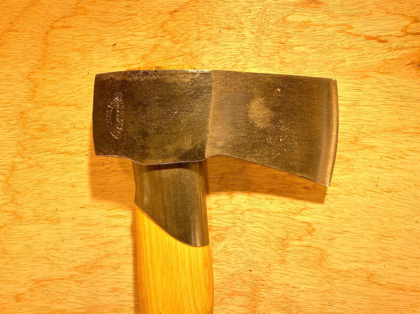 A close-up view of the Gransfors Bruk Small Splitting Axe 441 by GRF, featuring a hickory handle, resting on a wooden surface.