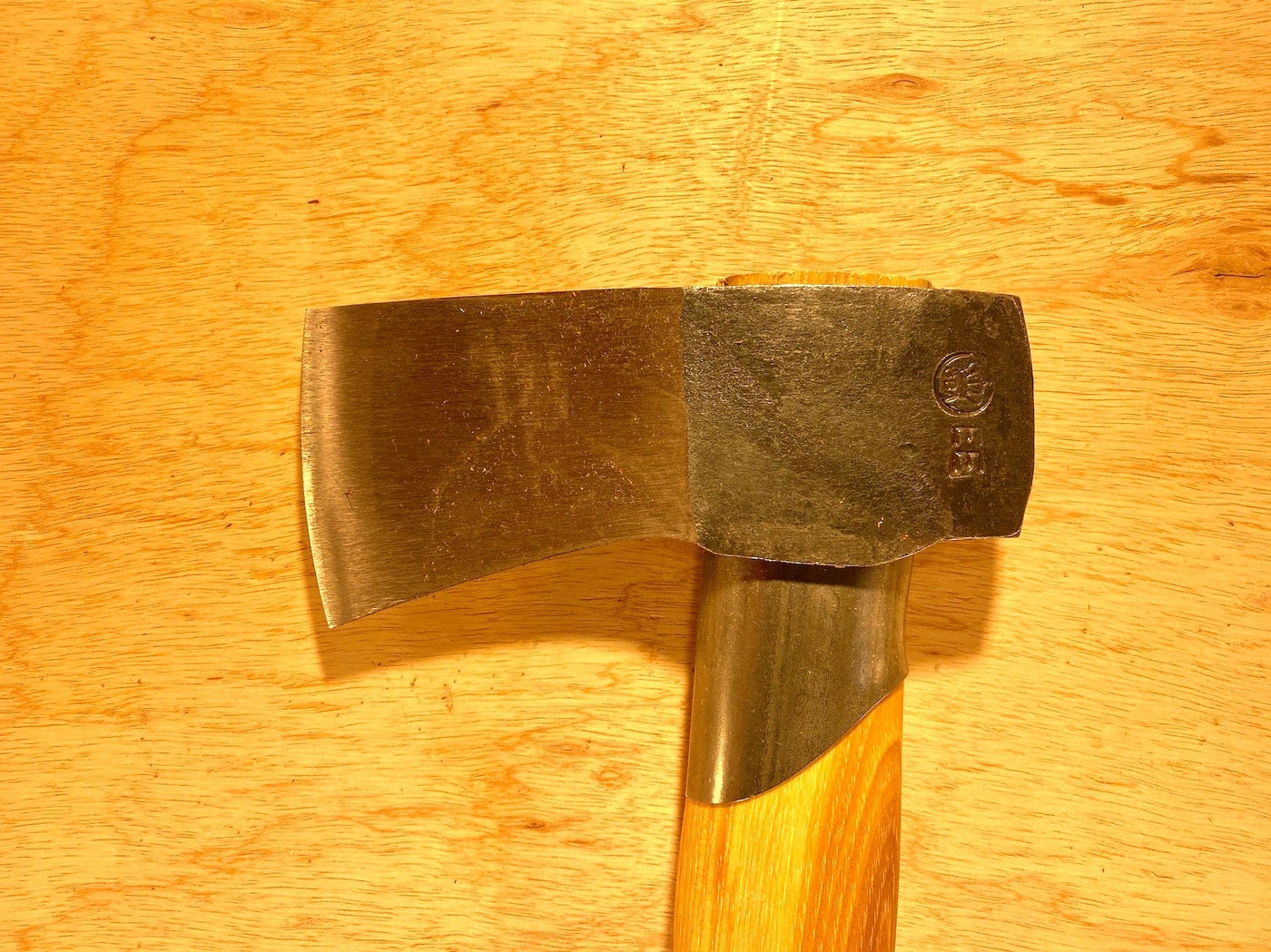 The Gransfors Bruk Small Splitting Axe 441 by GRF, featuring a metal head and hickory handle, rests on a wooden surface, complemented by a grain-leather sheath.