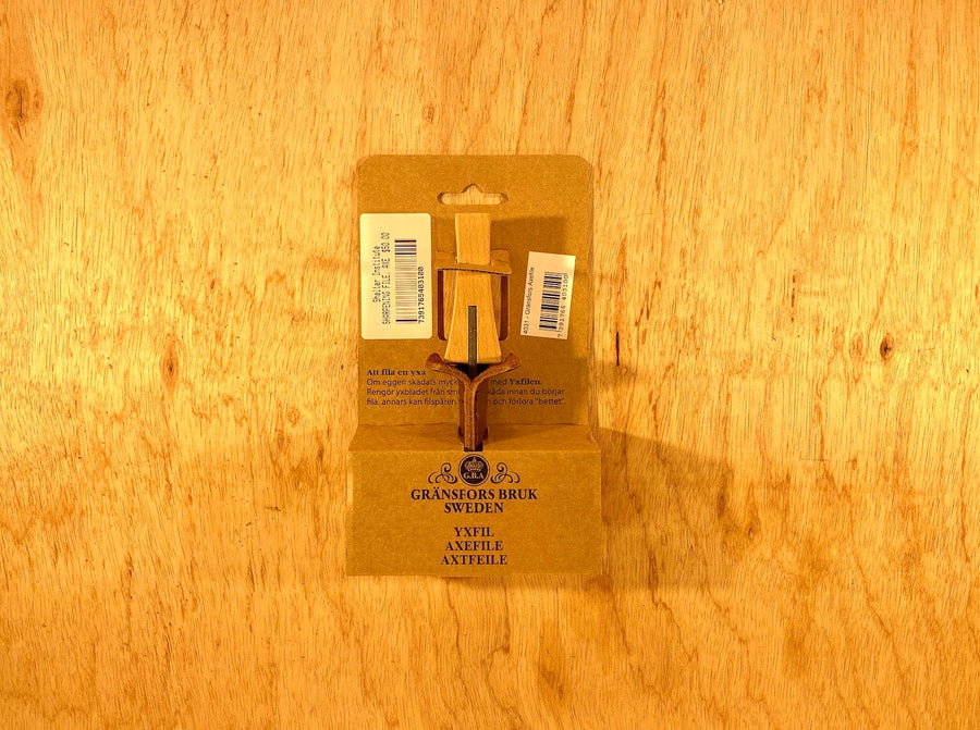 A GRF Gransfors Bruk Axe File, featuring a durable steel design, is nestled in its original packaging and displayed on a rustic wooden surface.