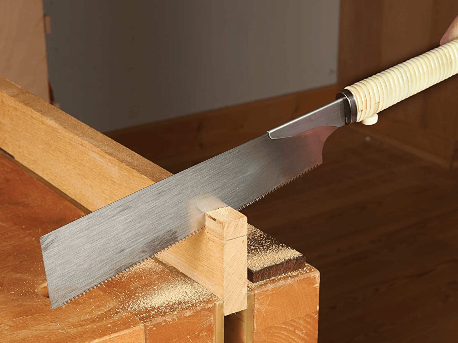 A skilled hand uses the BBT Gyokucho Crosscut Razorsaw 240mm to precisely cut wood secured to a workbench, demonstrating key woodworking skills.