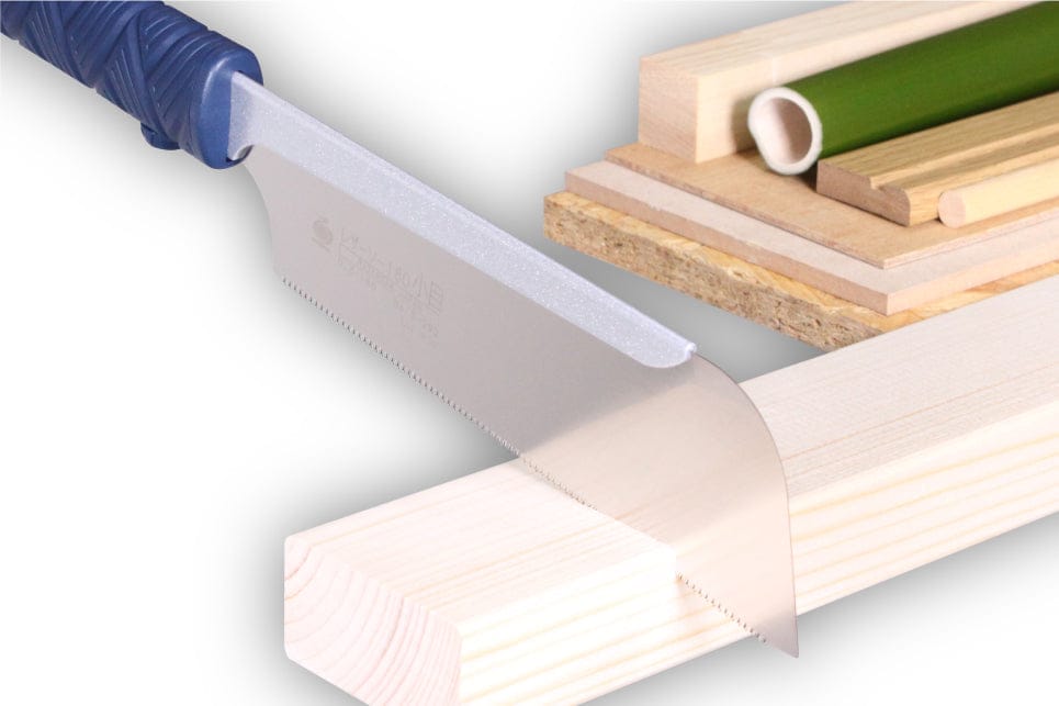 A Gyokucho 180 Komame Razorsaw by BBT, with its distinctive blue handle, effortlessly cuts through a piece of lumber while various wooden and bamboo materials are stacked in the background, showcasing this fine woodworking tool.