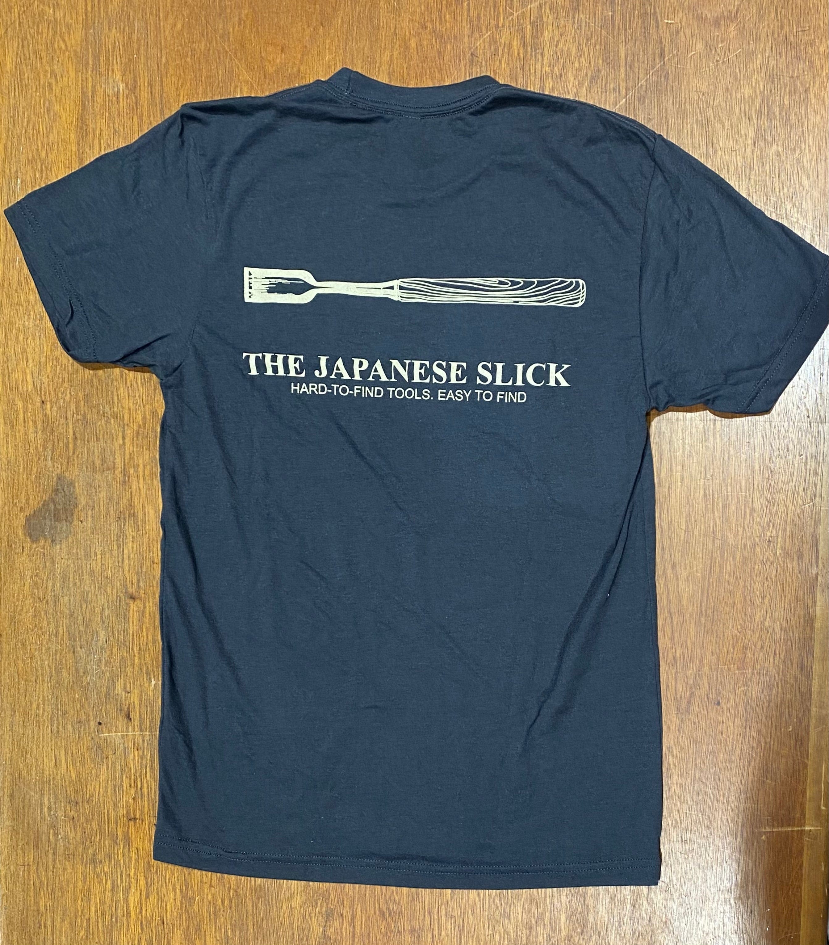 HighPine's "That is one Slick T-Shirt" in black on a wooden surface, showcasing a chisel graphic and the text: "THE JAPANESE SLICK - HARD-TO-FIND TOOLS, EASY TO FIND.