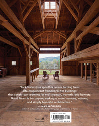 The barn’s exposed beams, crafted with traditional timber framing, echo the craftsmanship celebrated in "Hand Hewn: The Traditions, Tools, and Enduring Beauty of Timber Framing" by Ingram Content Group. Two chairs face the scenic view from the porch.