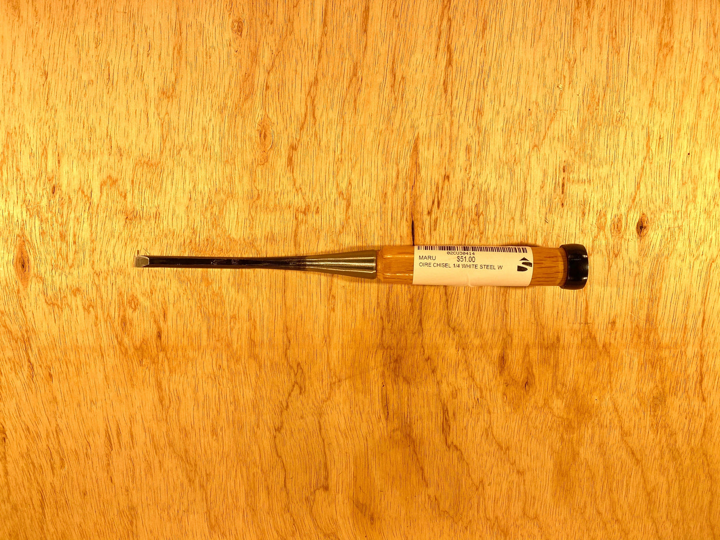 A compact flathead screwdriver, featuring a black handle and a label evocative of MARU's Fujikawa Oire Bench Chisels, is laid horizontally on a wooden surface.
