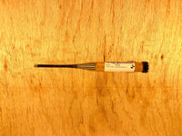 A compact flathead screwdriver, featuring a black handle and a label evocative of MARU's Fujikawa Oire Bench Chisels, is laid horizontally on a wooden surface.
