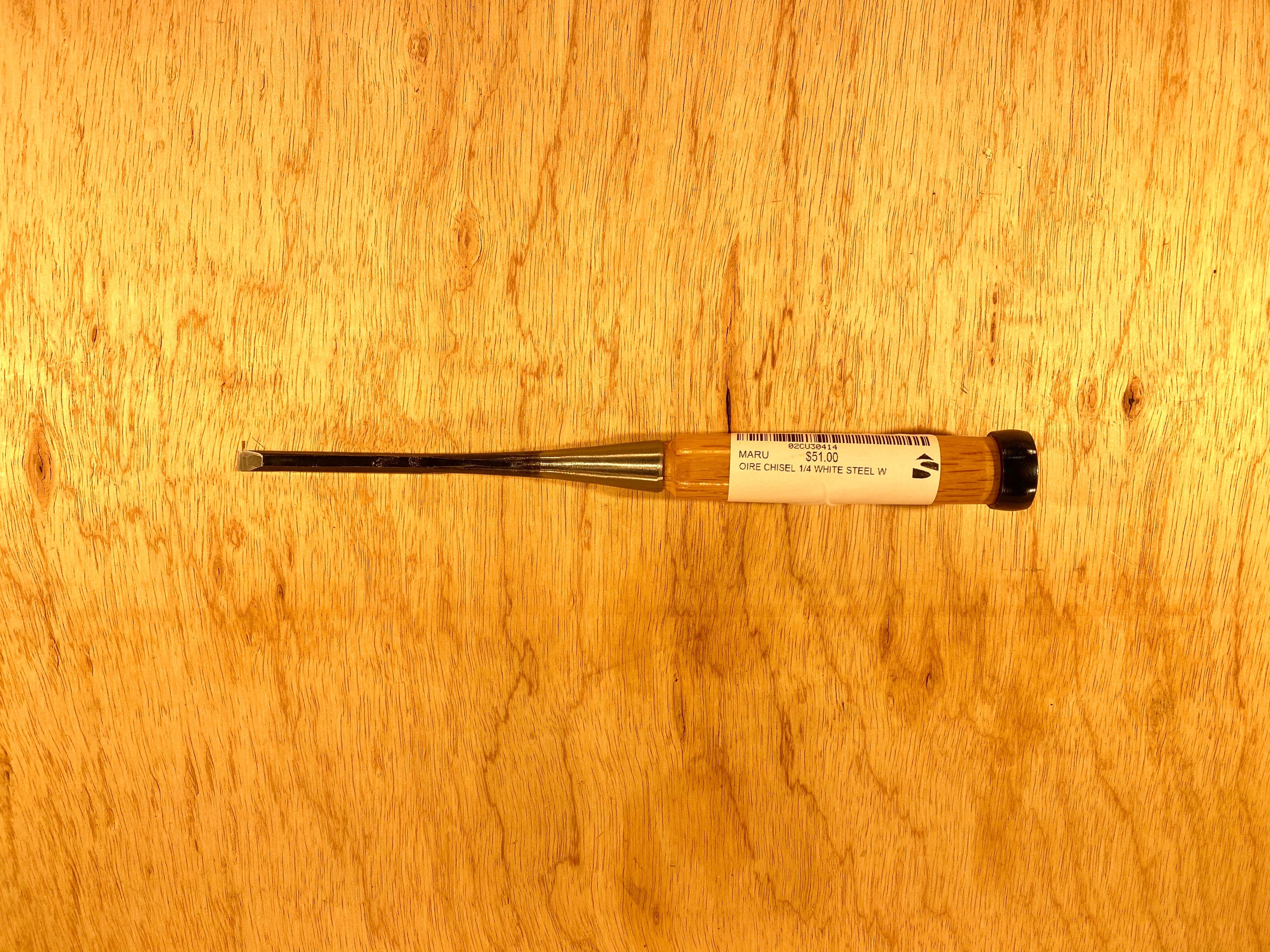 A compact flathead screwdriver, featuring a black handle and a label evocative of MARU's Fujikawa Oire Bench Chisels, is laid horizontally on a wooden surface.
