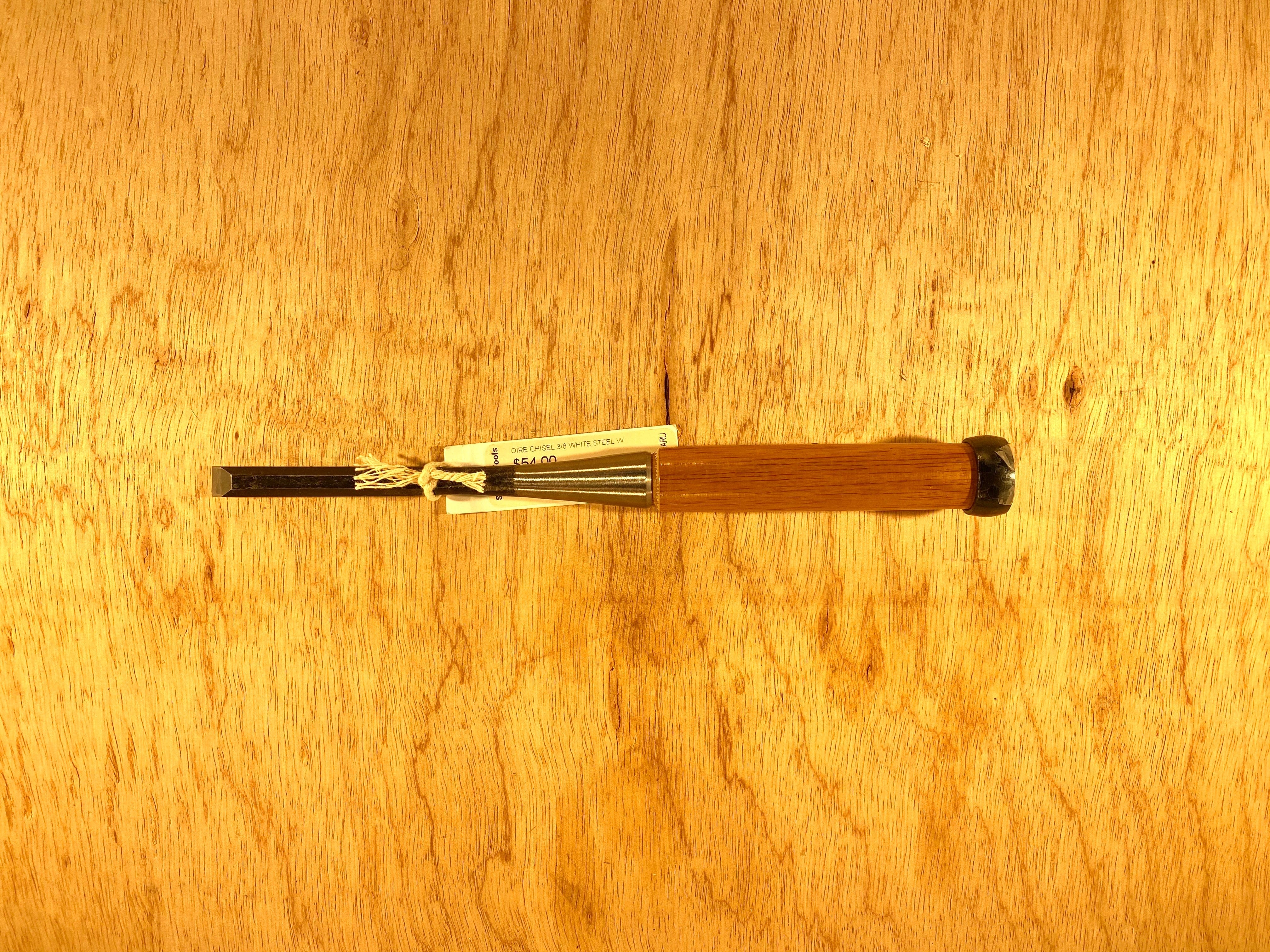 A professional-grade Fujikawa Oire Bench Chisel with a wooden handle lies on a wooden surface, showcasing the MARU craftsmanship akin to Japanese chisels designed with white steel laminated precision.