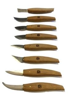 Eight Magari Carving Knives by MARU, featuring unique high-carbon-steel blades and smooth red-oak handles, are arranged vertically on a white background.
