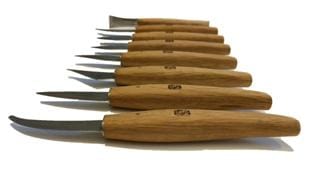 Eight MARU Magari Carving Knives with rich red-oak handles and high-carbon steel blades are arranged in a row on a white background, handles facing the camera and blades pointing away.