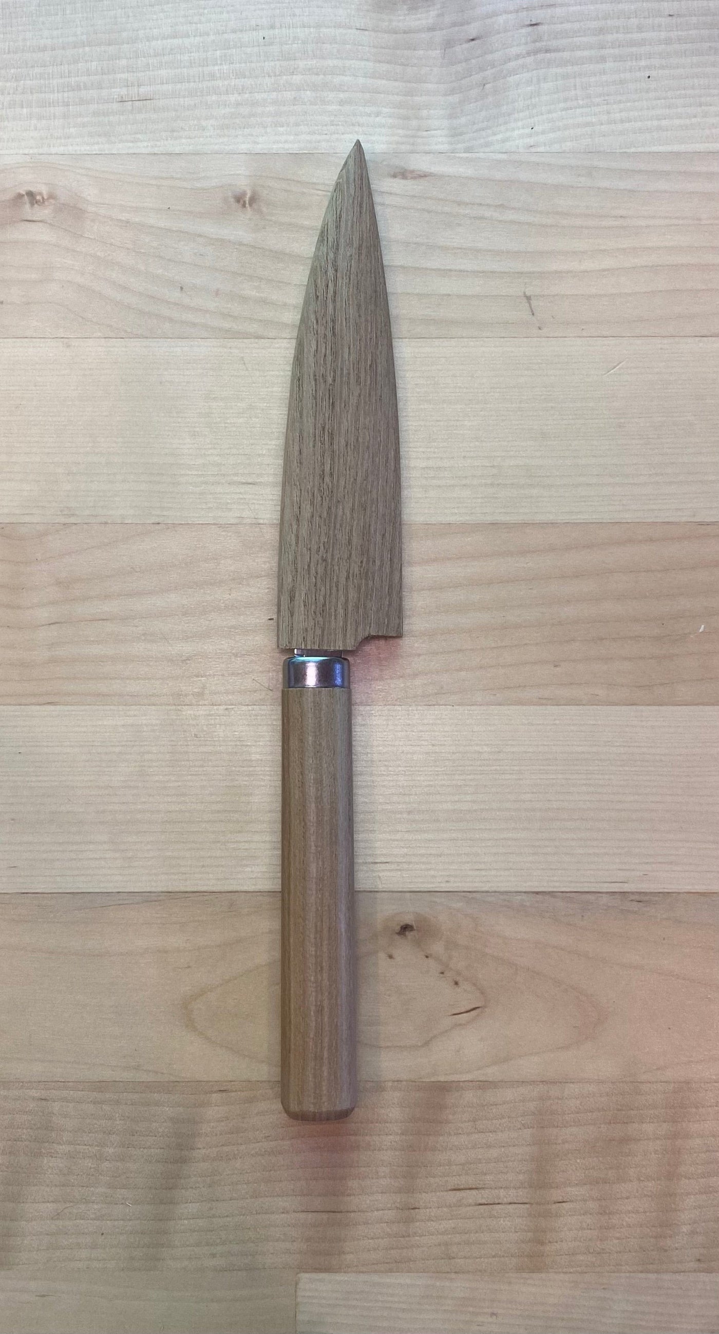 The MARU FRUIT KNIFE with a wide, short stainless steel blade and an oak handle lies on a light wooden surface.