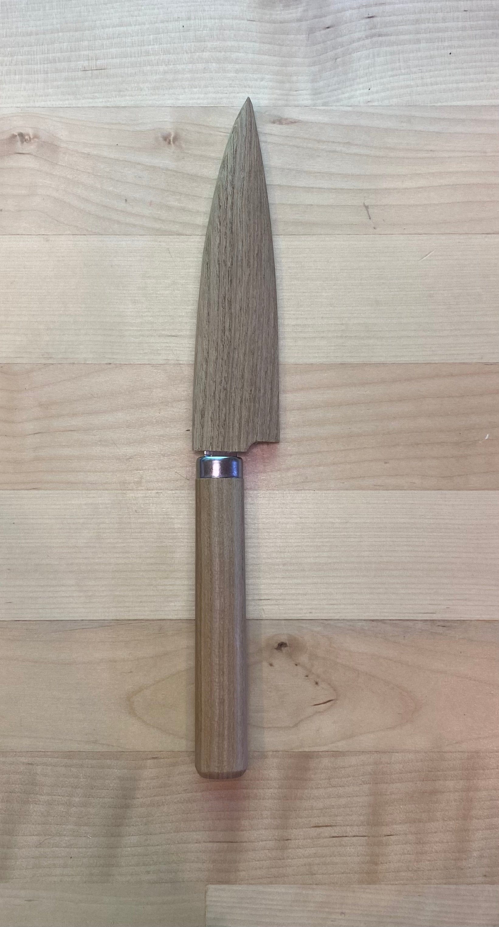 The MARU FRUIT KNIFE with a wide, short stainless steel blade and an oak handle lies on a light wooden surface.