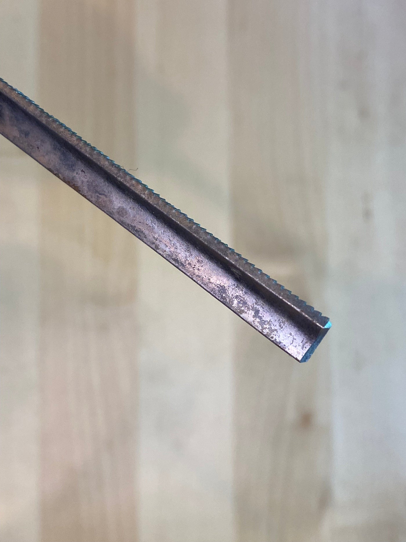 Close-up of the serrated edge of a MARU Iwasaki Half Round Ex Fine W/Grip on a light wooden background.