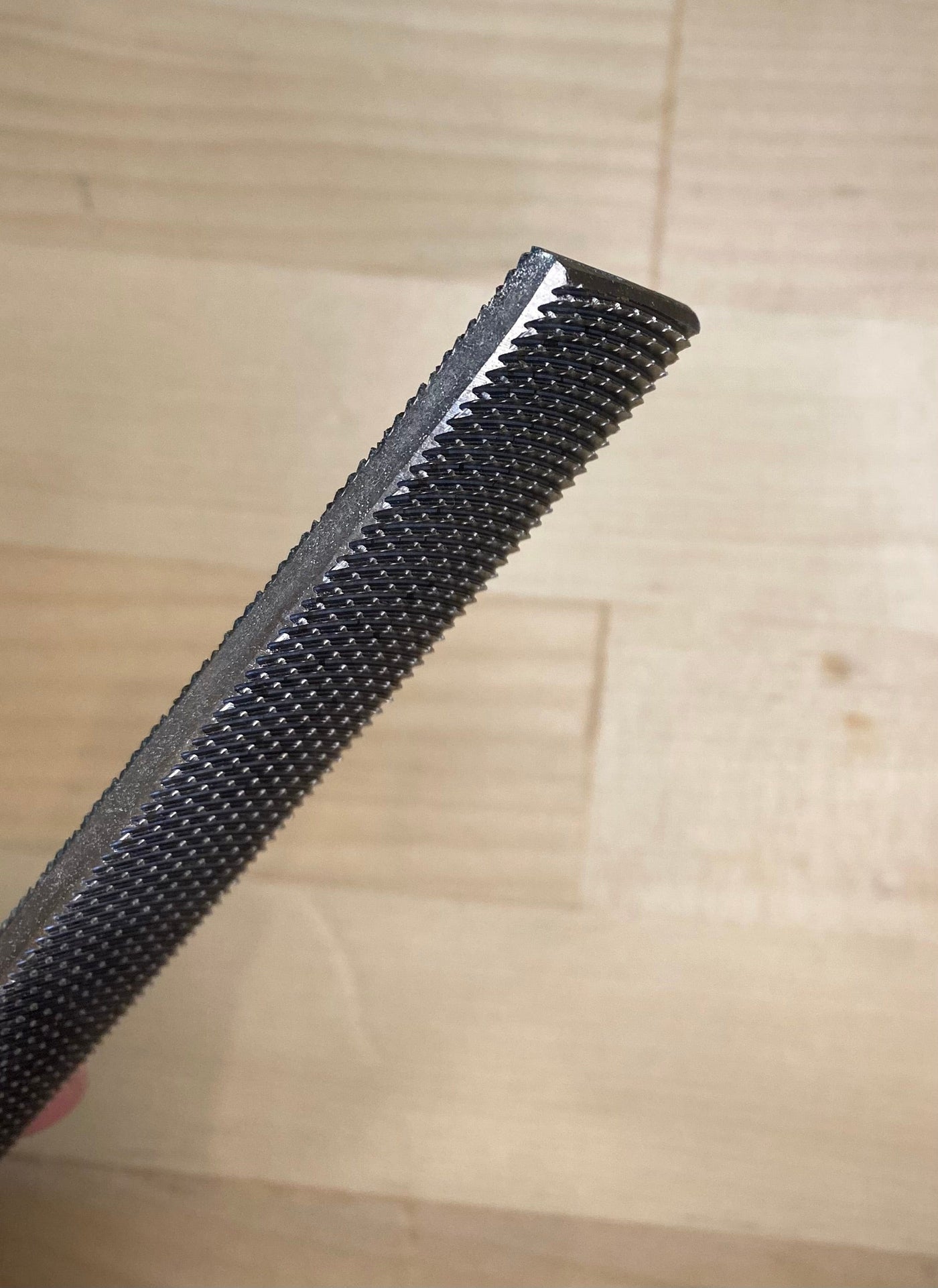 Close-up of a MARU Iwasaki Wood File featuring a textured surface, displayed against a light wooden background, highlighting the precision and craftsmanship synonymous with Japanese wood-shaping tools.