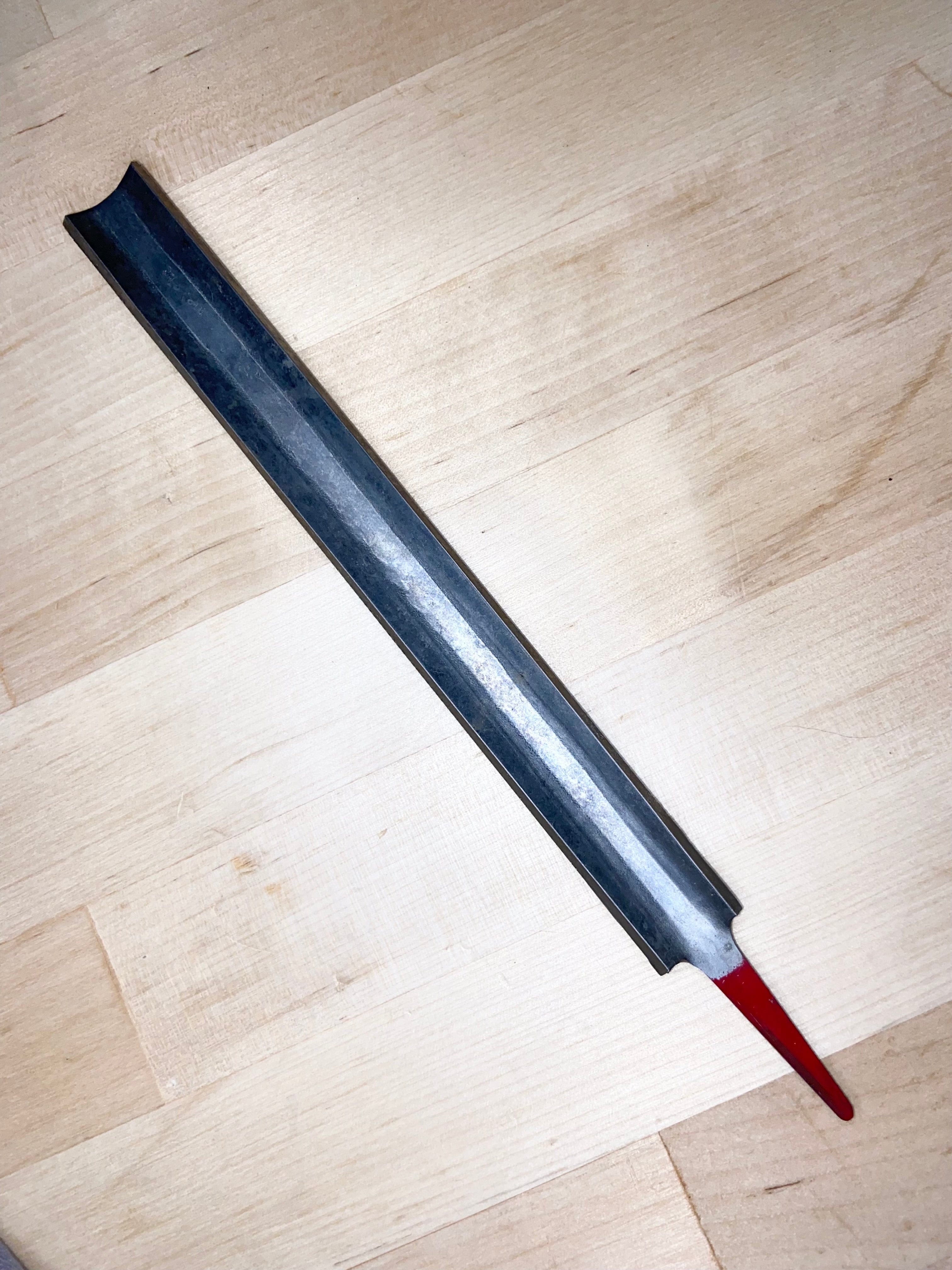 A MARU Iwasaki Half Round Fine Cut Wood File lies diagonally on a light wooden surface, featuring a chemically polished and red-painted end.