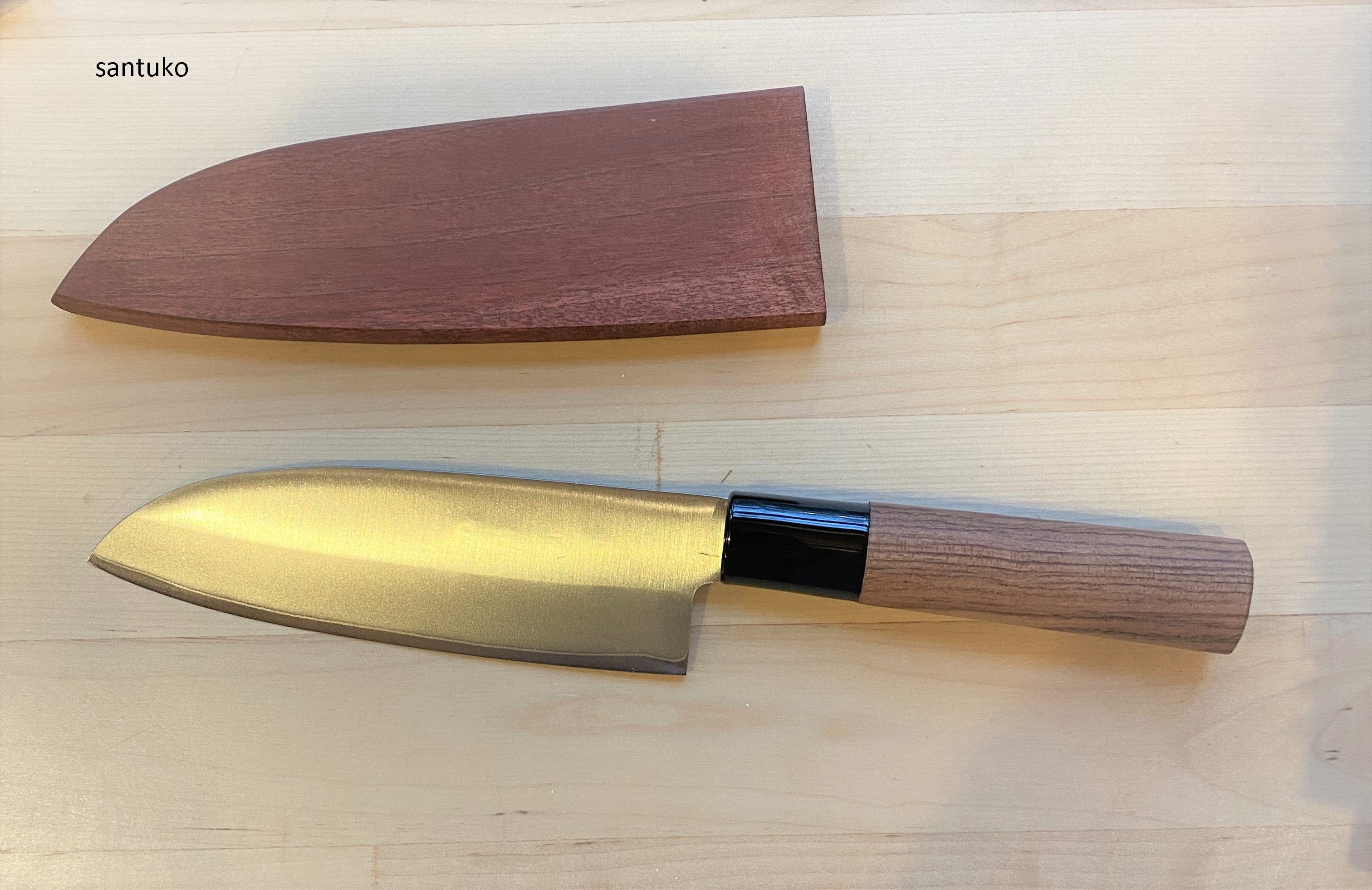 A MARU Japanese Kitchen Knife with a wooden handle and blade sheath lies on a light wood surface. The uncovered blade is below the sheath, and santoku is shown in the top left corner. Santoku knives are valued in Japanese kitchens.