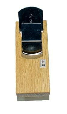 A MARU Compass Plane, crafted from Japanese White Oak, features a hand-forged lamination metal blade positioned at the center.