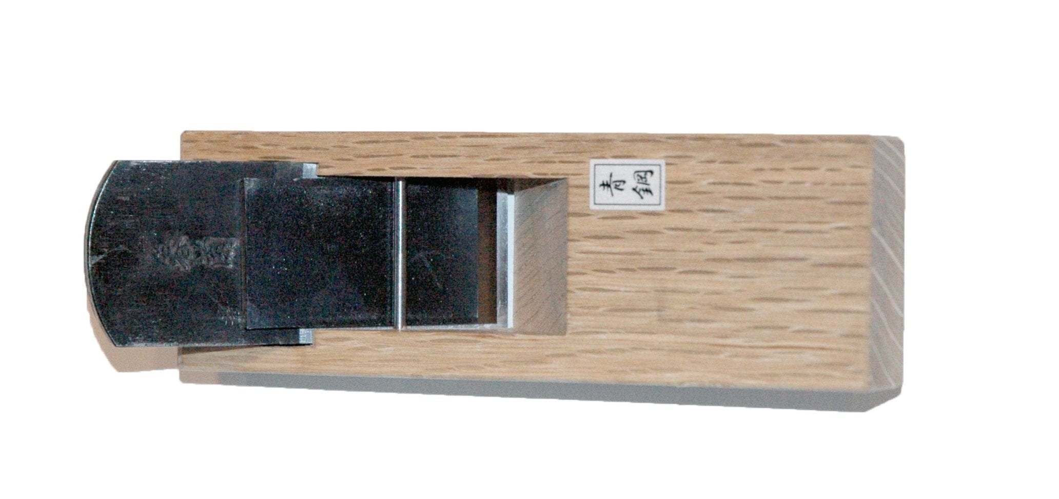 The MARU Compass Plane, crafted from Japanese White Oak and featuring a steel blade visible at the top, is perfect for smoothing or shaping wood surfaces. The hand-forged lamination of its components ensures precision and durability.