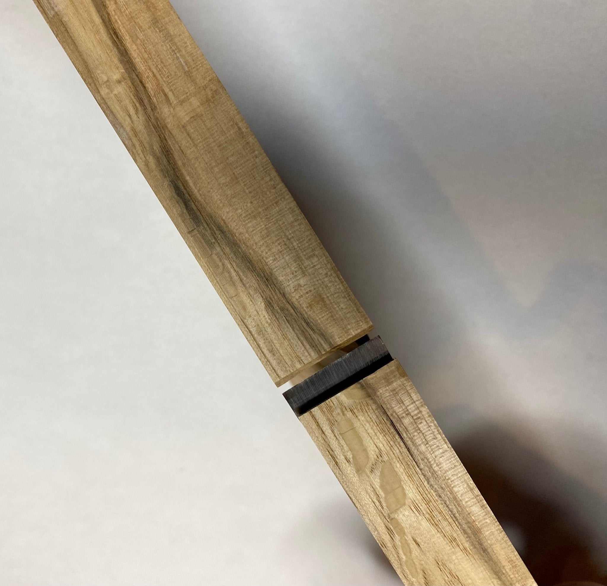 Close-up of two light wood pieces with a straight joint and thin dark seam, crafted using the MARU Japanese Rabbet Plane-White Oak, highlighting grain patterns and precise joinery.