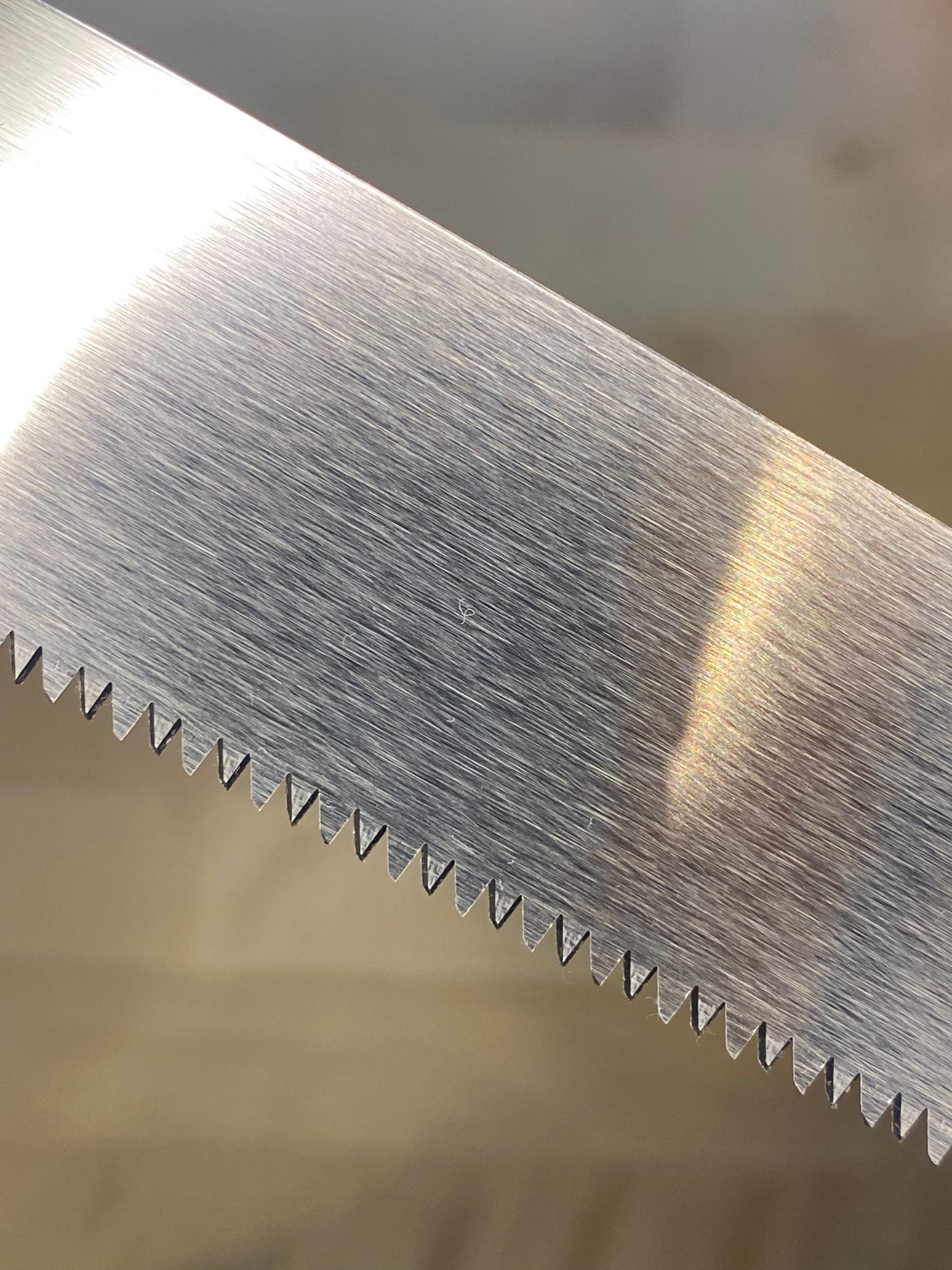 Close-up view of MARU's Small Sheathed Japanese Hand Saw blade with sharp, impulse-hardened serrated teeth, perfect for fine woodworking.