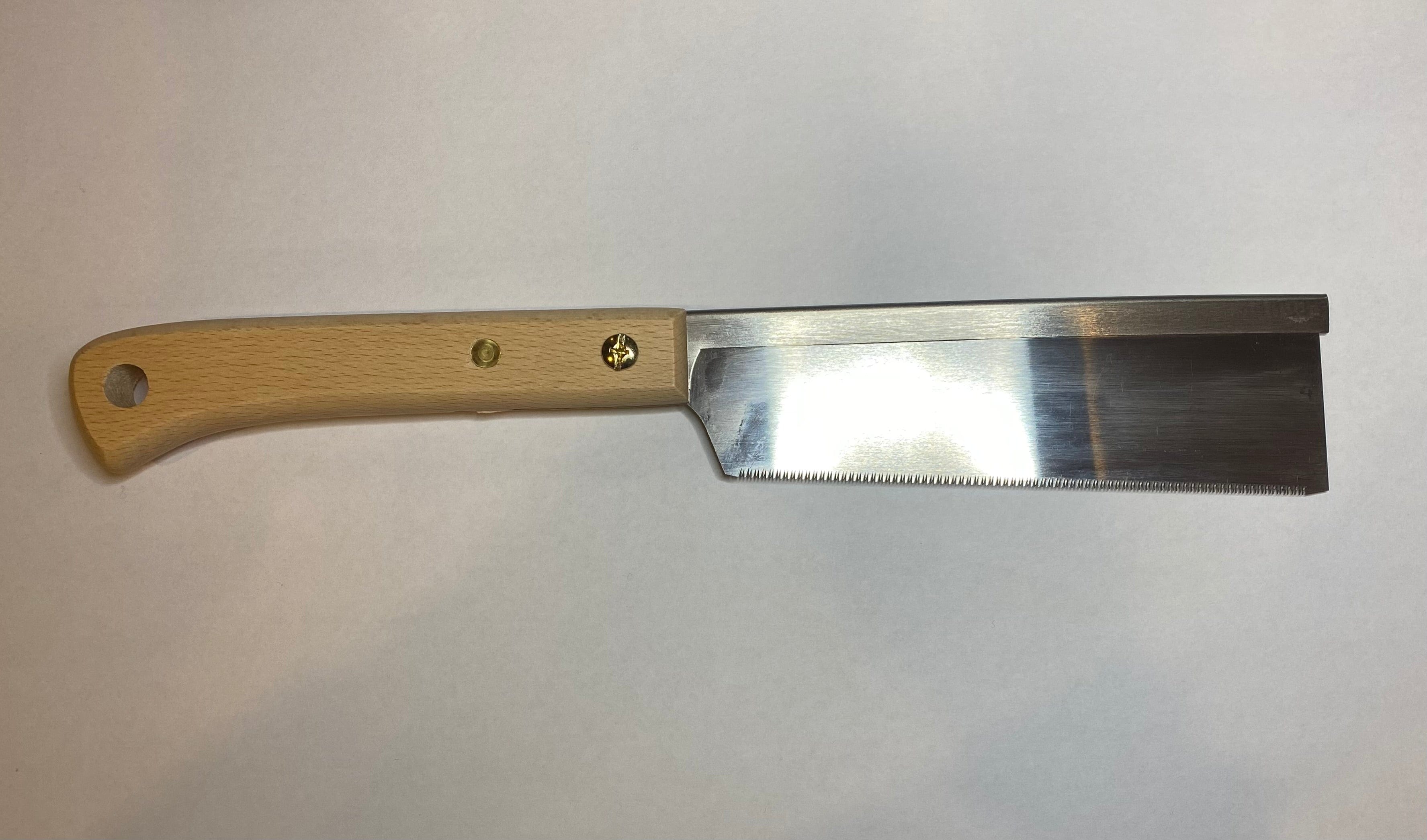 A MARU Japanese Craft Saw, featuring a beech wood handle and a sharp, straight metal blade, is elegantly displayed on a plain white surface.