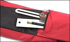 A MARU Hand Saw Bag in striking red and black is partially open, showcasing a pencil, sharpener, and divider tool inside. This pouch is perfect for woodworking accessory storage and ensures efficient tool organization.