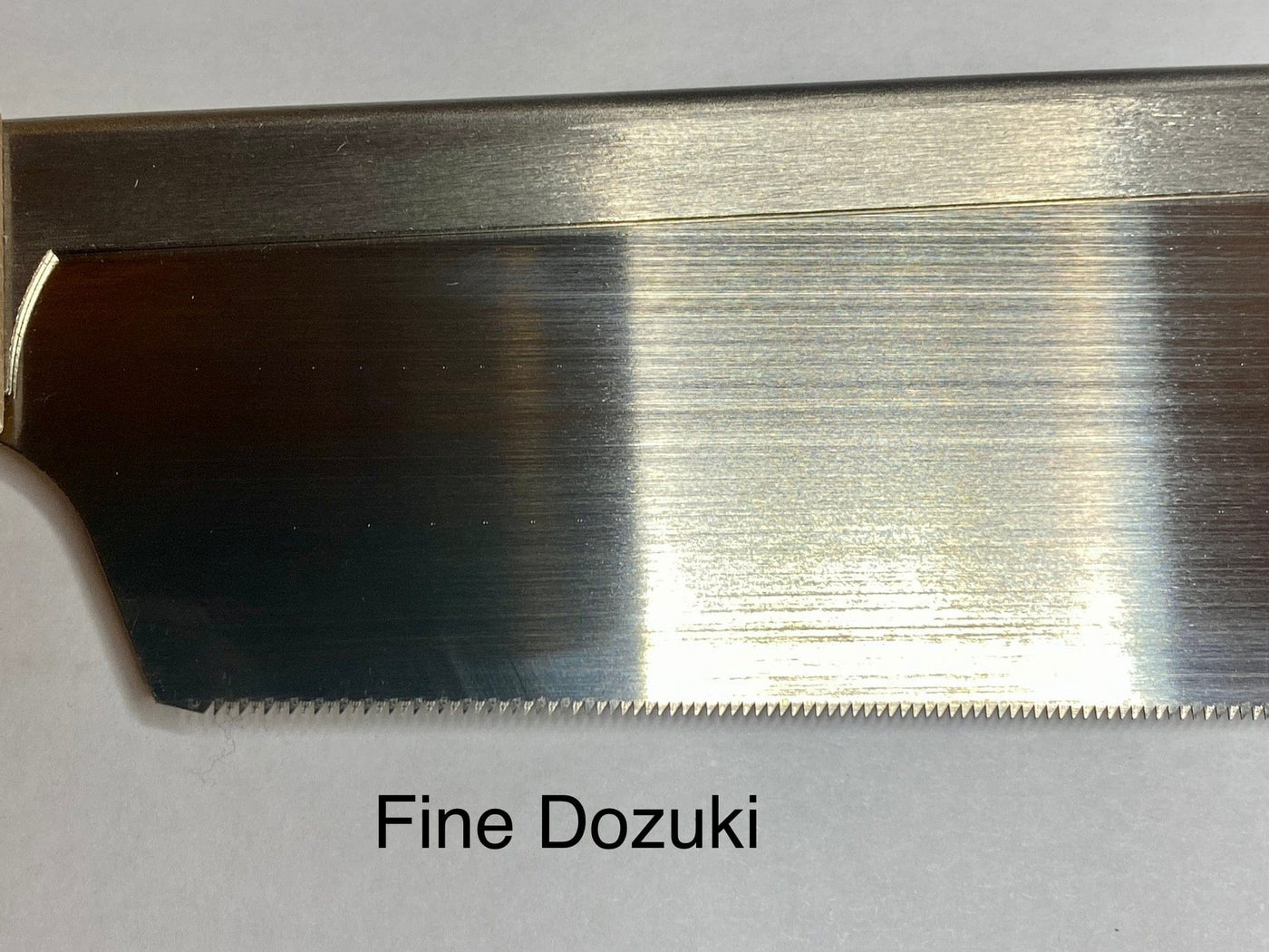 Close-up of a MARU Japanese Craft Saw blade, showcasing precision akin to a ryoba. Its sharp, finely spaced teeth are set against a plain white background, emphasizing craftsmanship and the ergonomic grip of its beech wood handle.