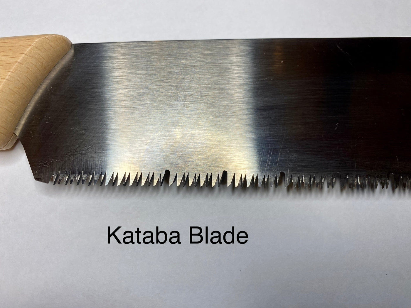 Close-up of a Japanese Craft Saw blade featuring sharp teeth and a beech wood handle on the left. The image displays Japanese Craft Saw beneath it. Brand: MARU.