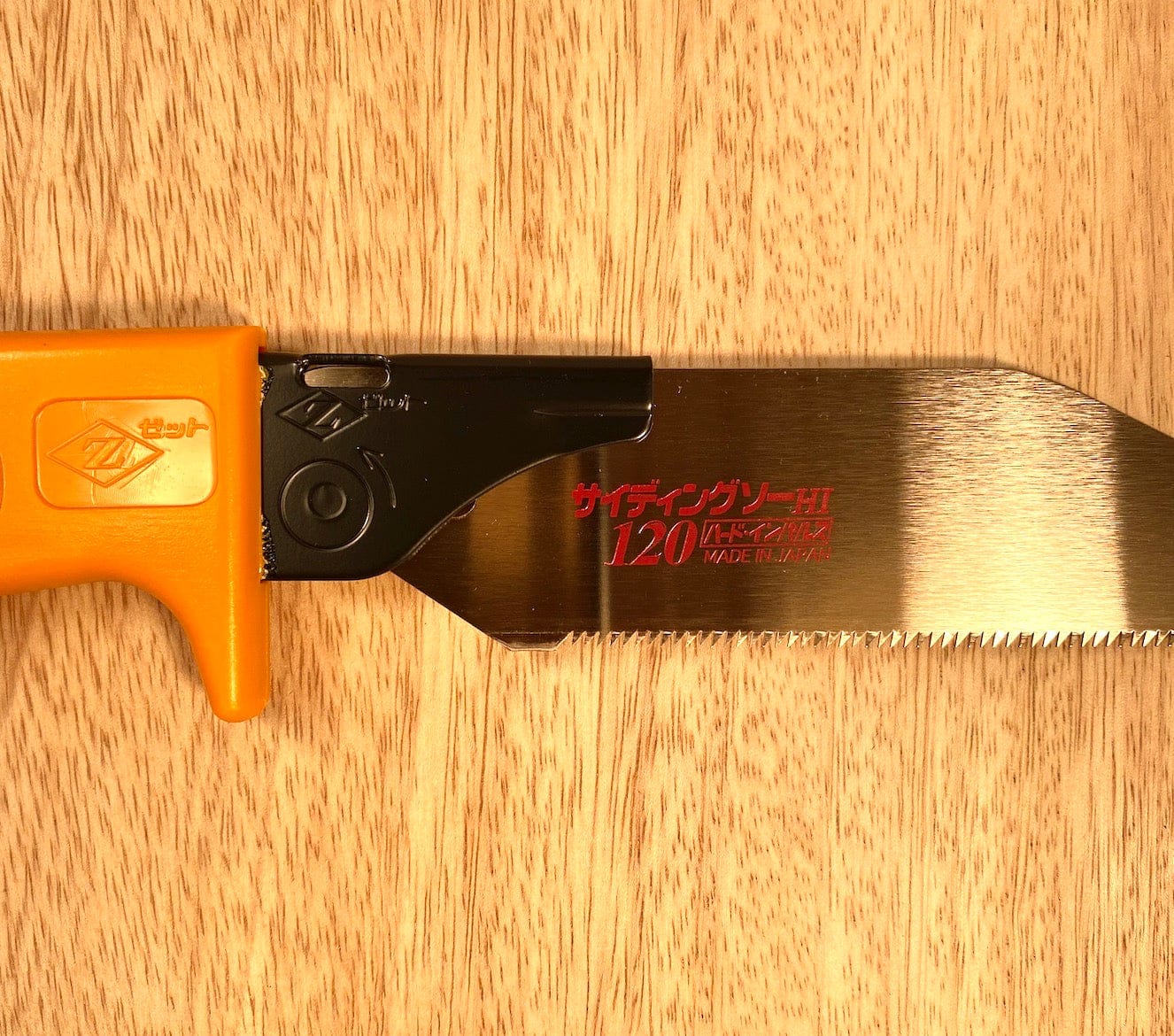 A compact Siding Saw by Z-Saw from the brand MARU, featuring a yellow handle and a metallic blade with red text, placed on a wooden surface.
