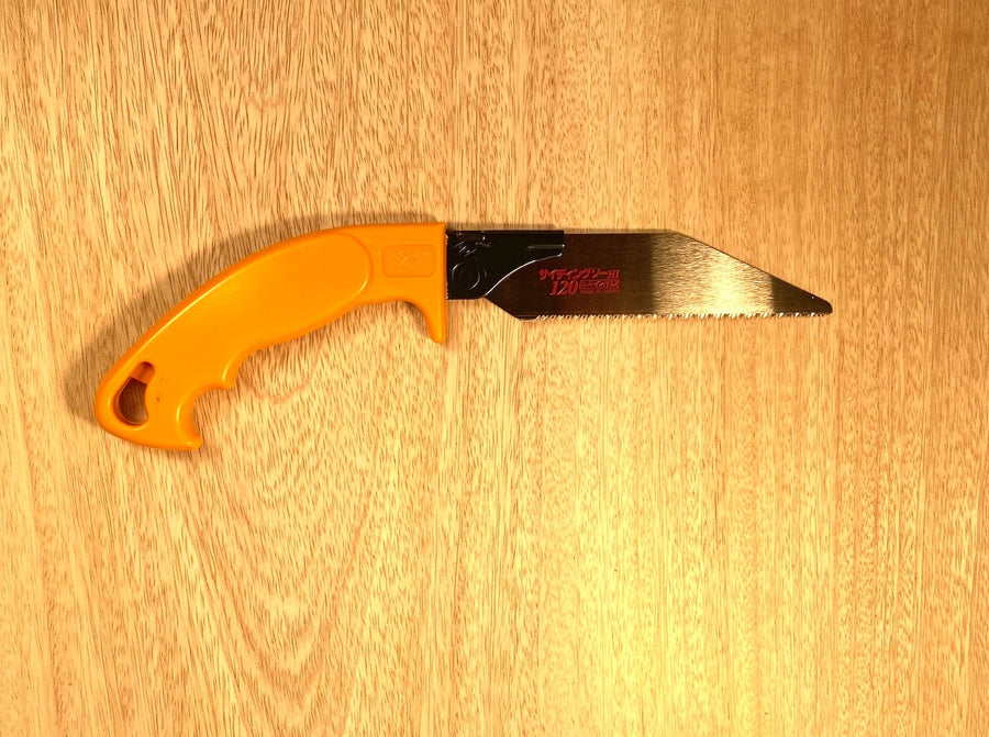 The Siding Saw by Z-Saw from MARU, featuring a compact design with an orange handle and a short, serrated blade, rests on a wooden surface, ready to cut siding.