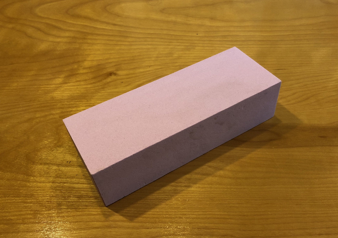 A rectangular pink eraser is placed on a wooden surface, nestled beside my 220 Grit Water Stone from MARU.