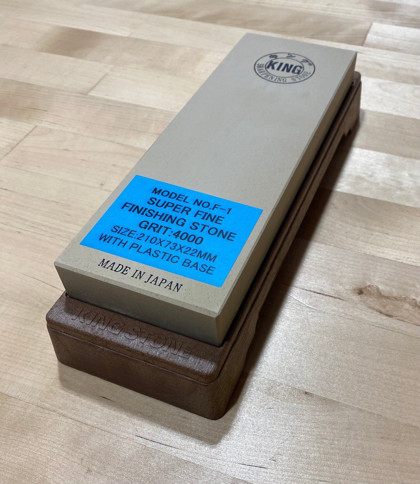 A 4000 Grit King Water Stone by MARU, featuring a wooden base and marked as "Super Fine Finishing Stone Grit: #4000" and "Made in Japan," is placed on a wooden surface. This water stone offers an exceptional polishing experience for flawless results.