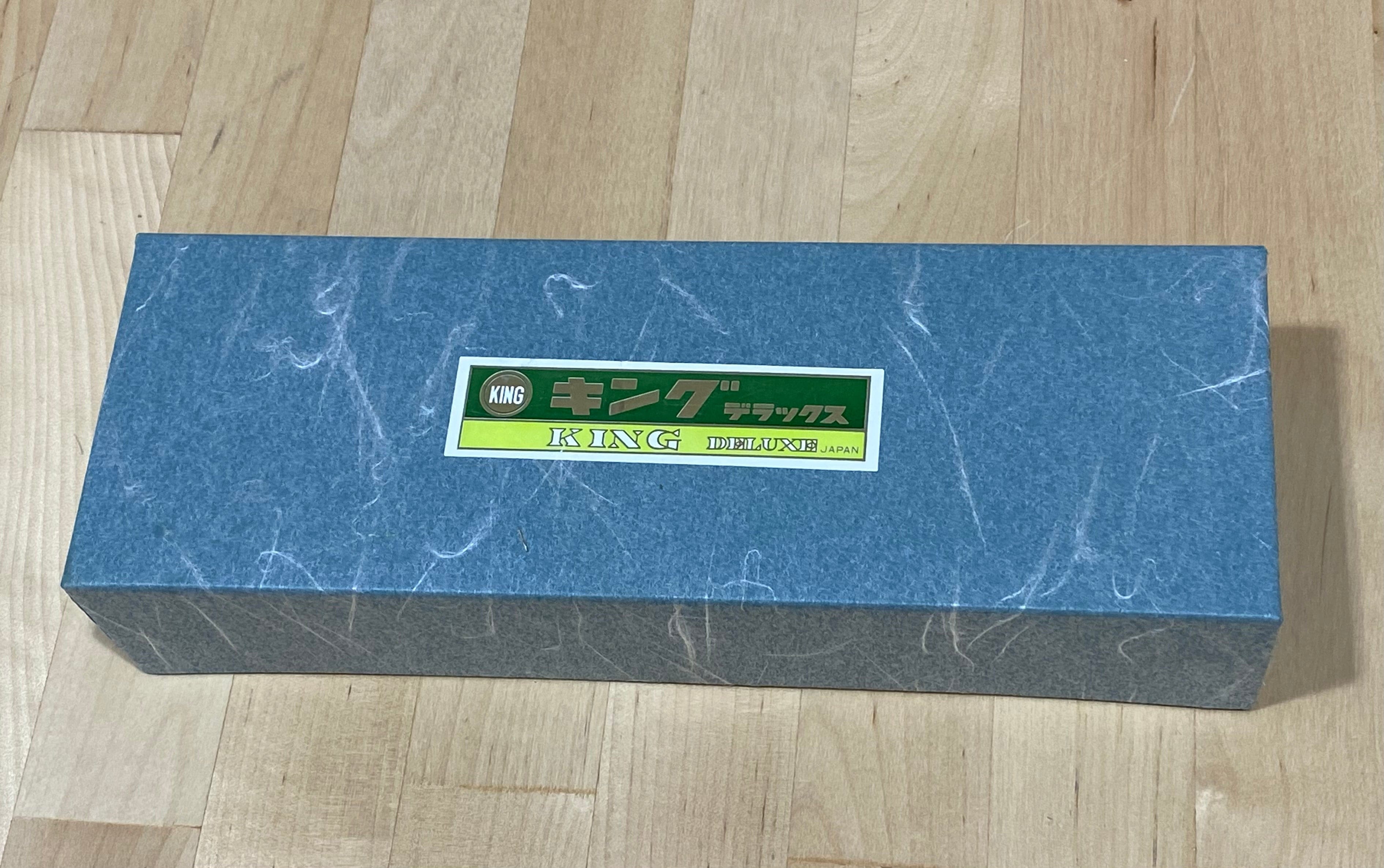 A blue rectangular box labeled "MARU," featuring a 4000 Grit King Water Stone, rests elegantly on a wooden surface.