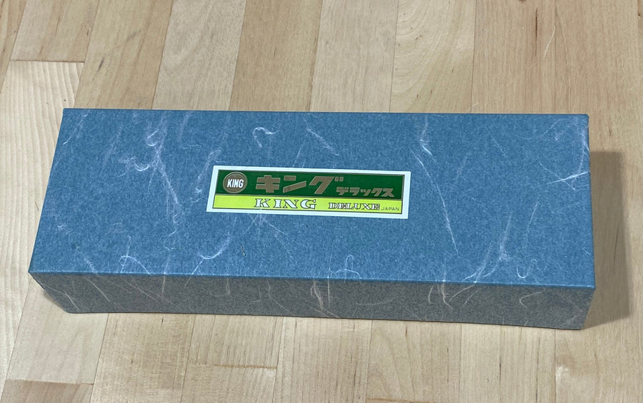 A blue rectangular box labeled "MARU," featuring a 4000 Grit King Water Stone, rests elegantly on a wooden surface.