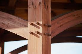 Close-up of a timber frame structure featuring interlocking joints and oak wedges, showcasing traditional woodworking techniques with Northcott Wood Turning's Pegs, Dovetail Shims, Wedges, and GRK Packages for Timber Frame Kits.