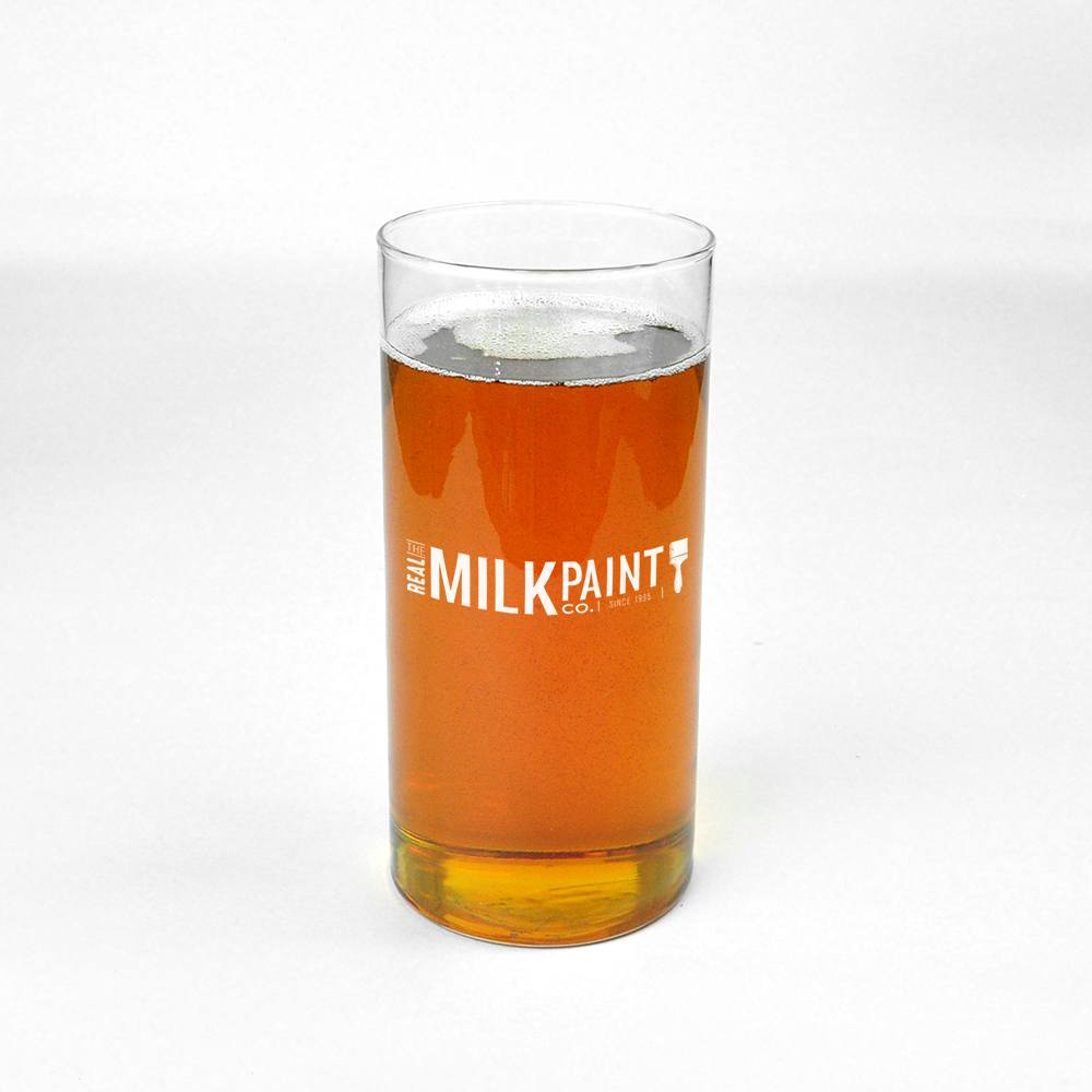 A clear glass filled with amber liquid labeled "RMP" stands against a plain white background, highlighting its environmentally friendly and food contact approved formula, representing the Pure Tung Oil product.