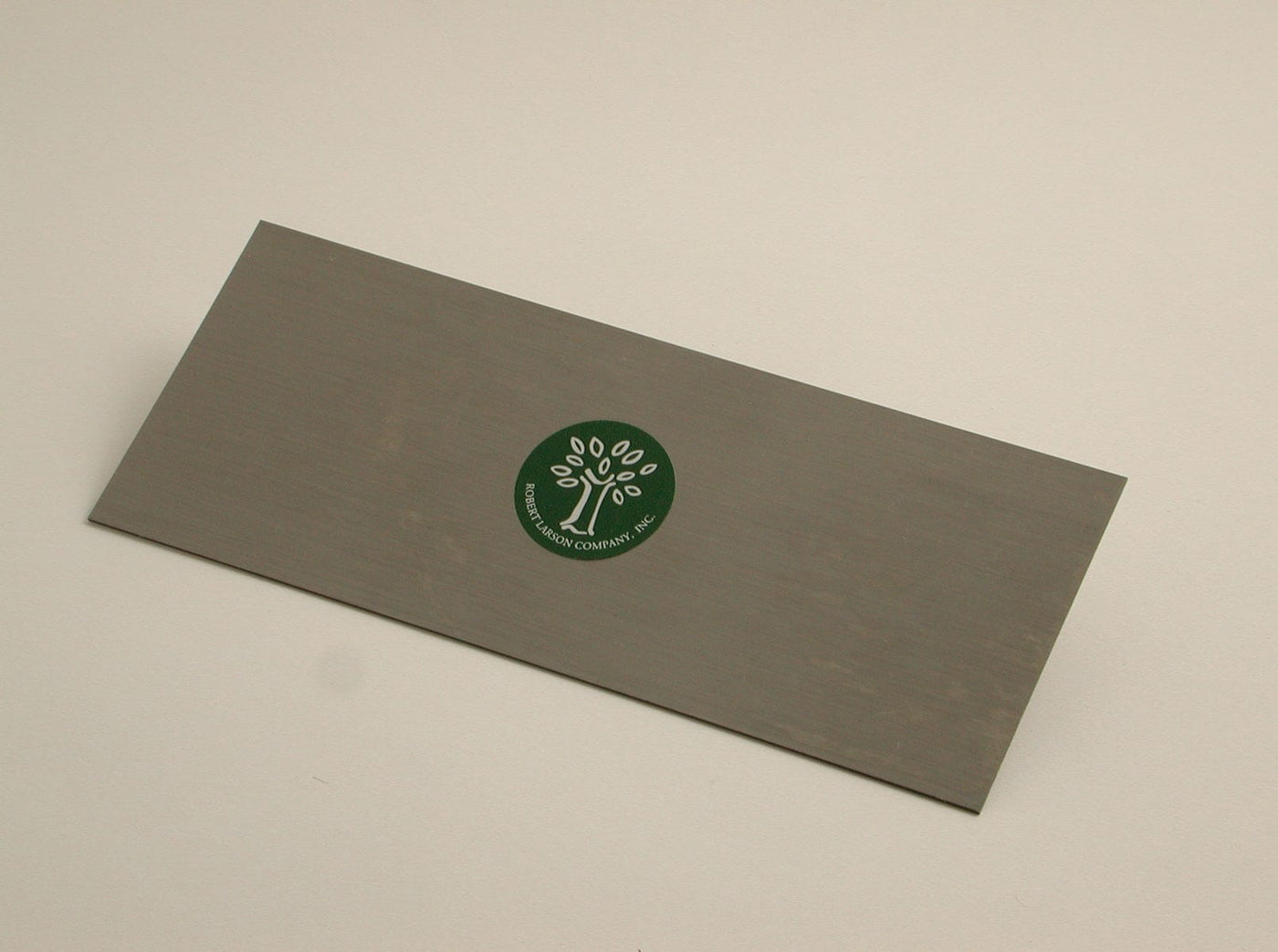The Cabinet Scraper by ROB is a rectangular metal tool featuring a green circular sticker with a tree logo and the text "Brookstone Company Inc.," suggesting craftsmanship similar to German steel for durability and precision.