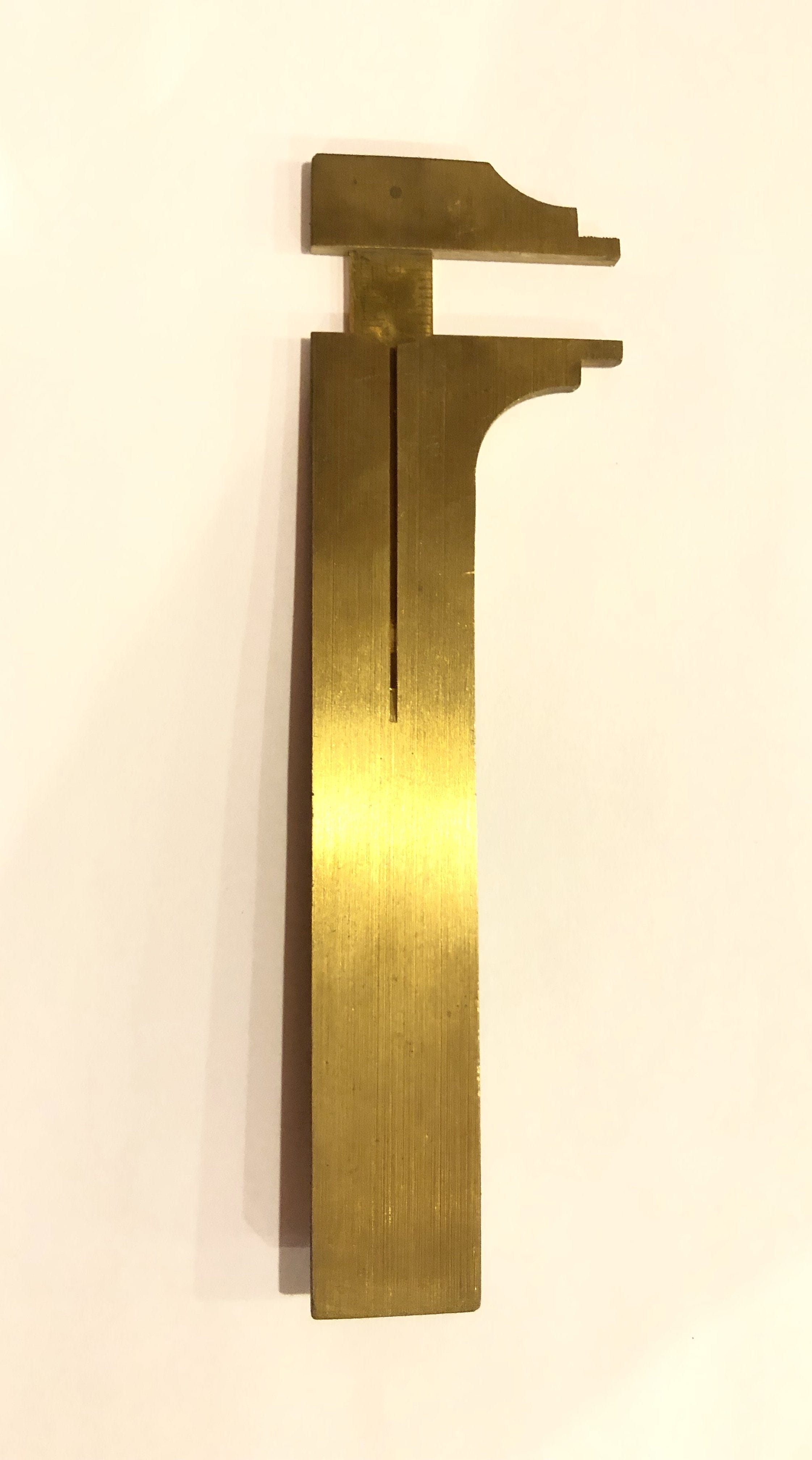 The compact ROB Brass Caliper, designed with a brass jaw on a white background, precisely measures in both inches and millimeters.