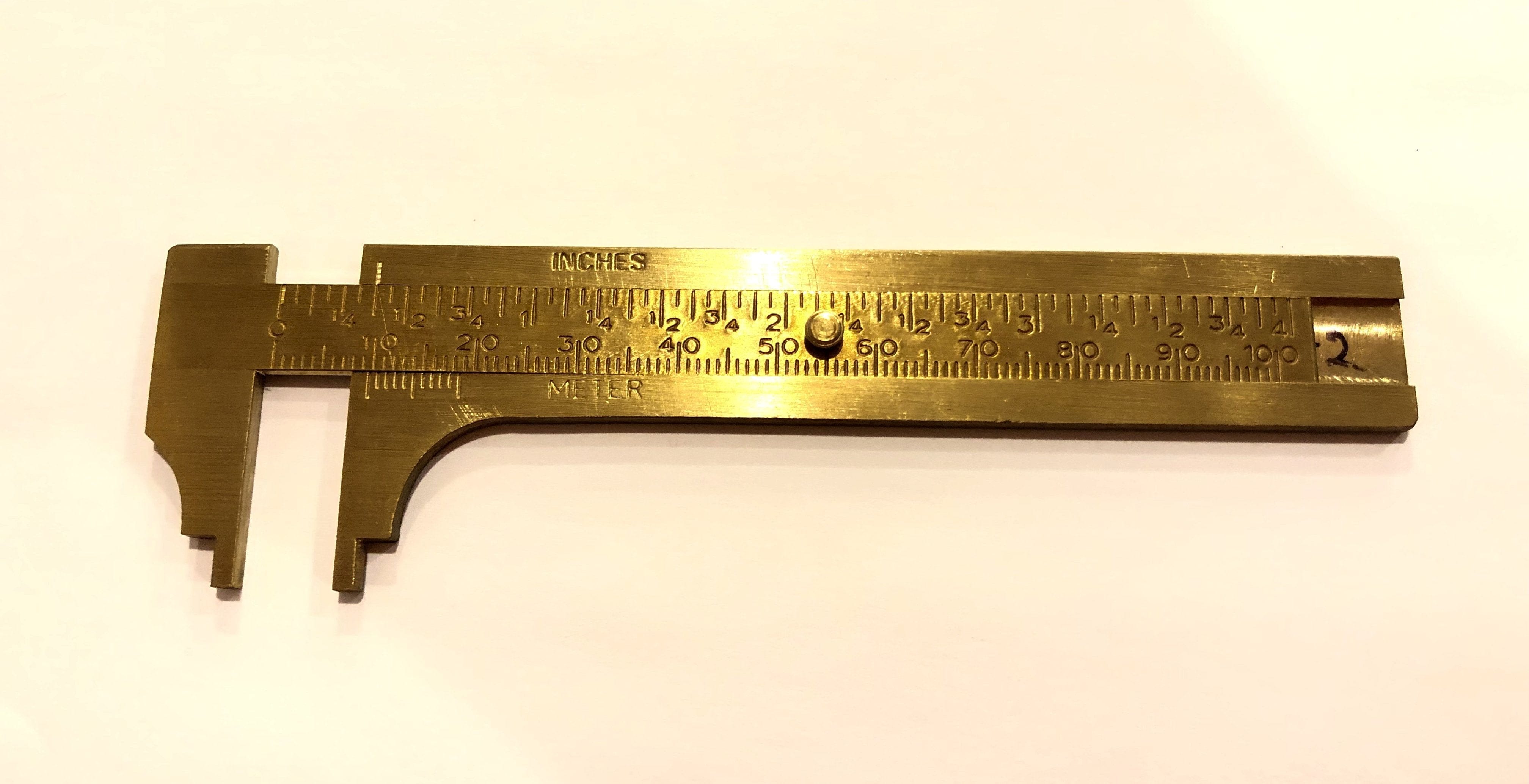 The ROB Brass Caliper is displayed against a white background, highlighting its compact design and dual measurement capabilities in inches and millimeters.