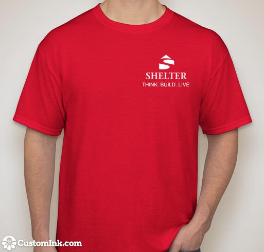 A person wearing a red Satisfaction Tshirt by Shelter Institute featuring the "SHELTER" logo and the phrase "THINK. BUILD. LIVE" on the front, with a CustomInk.com watermark at the bottom left corner.