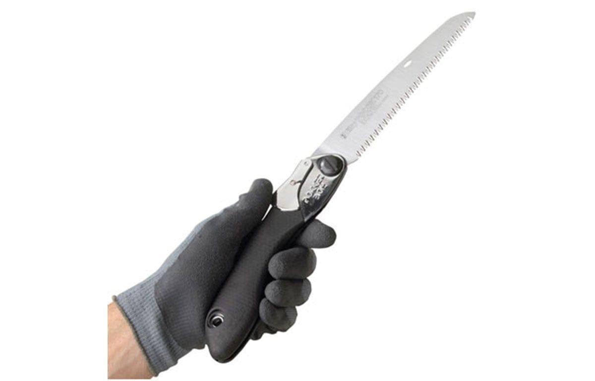 A gloved hand grips the BBT Pocket Boy 170 Folding Saw, its toothed blade securely locked for safe use.