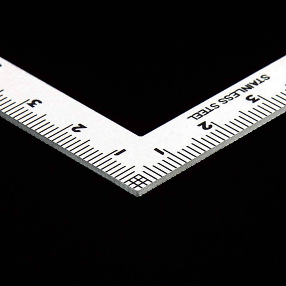 The SHWA Shinwa Mini Square 10x5 cm is a stainless steel ruler with metallic scales featuring both metric and imperial measurements on a black background.