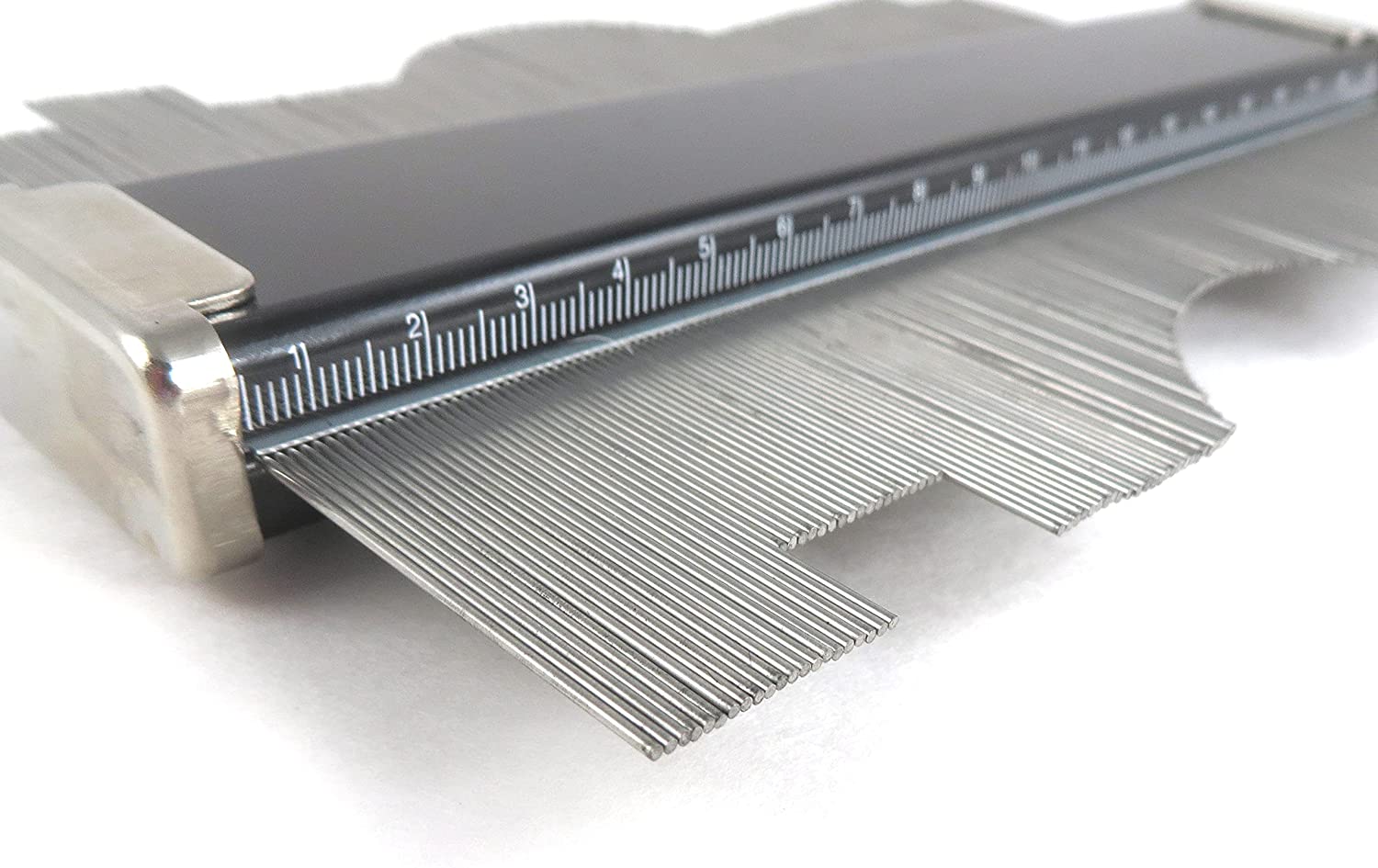 A close-up of the Shinwa Profile Gauge by SHWA, featuring stainless steel pins and a ruler, beautifully capturing an irregular shape.