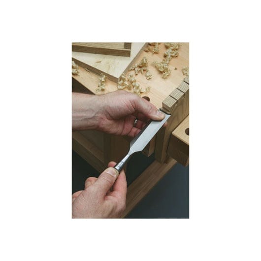 Hands skillfully wielding Stanley Sweetheart Socket Chisels by STN on a workbench, surrounded by delicate wood shavings. Crafted from high-carbon chrome steel, these chisels echo timeless craftsmanship rooted in Sheffield, England.