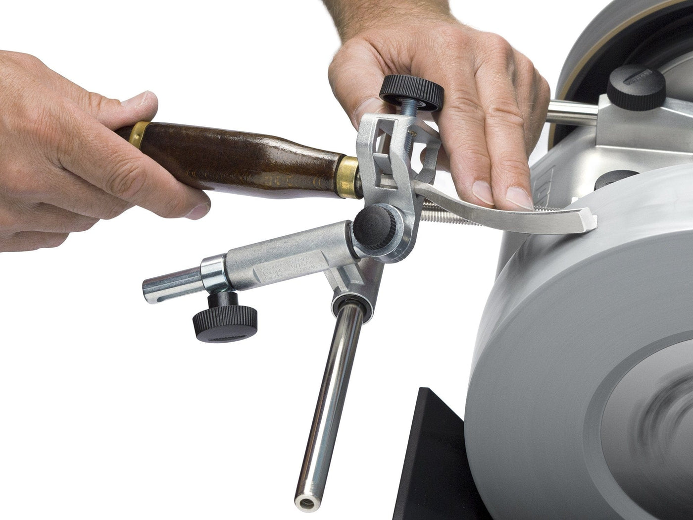 Close-up of hands using the TOR Tormek Gouge Jig to sharpen a chisel on a grinding wheel, demonstrating precise woodturning technique with this essential sharpening tool.