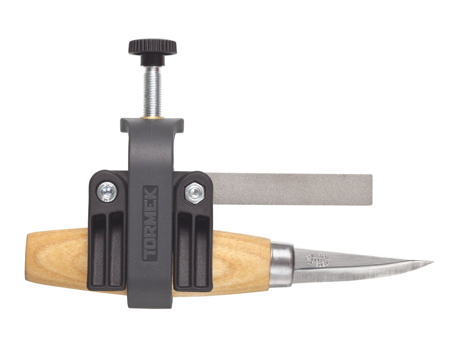 A carving knife with a wooden handle is secured in the TOR Tormek Small Knife Holder, easily attached to a flat sharpening stone to sharpen small knife blades with precision.