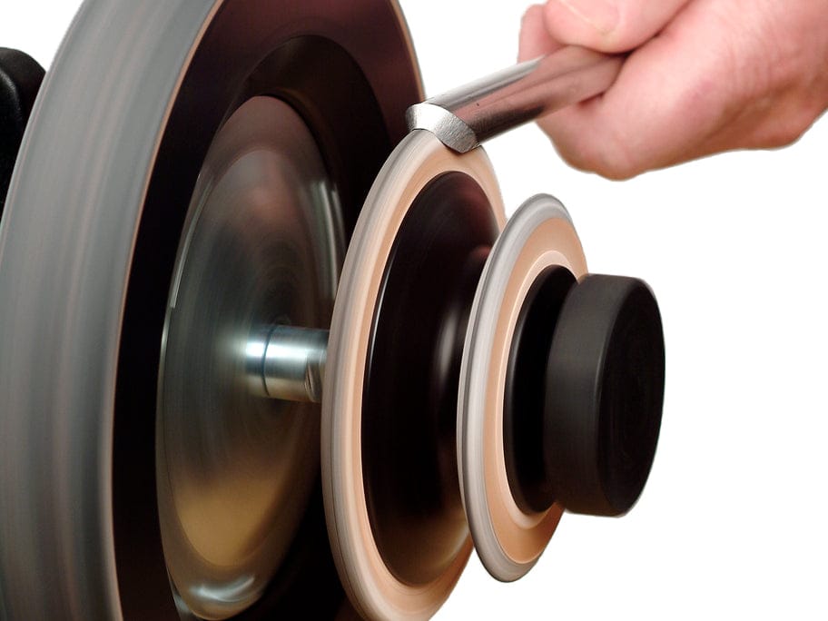 Close-up of a hand holding a turning gouge being sharpened on the Tormek Profiled Honing Wheel by TOR, in motion against a white background.