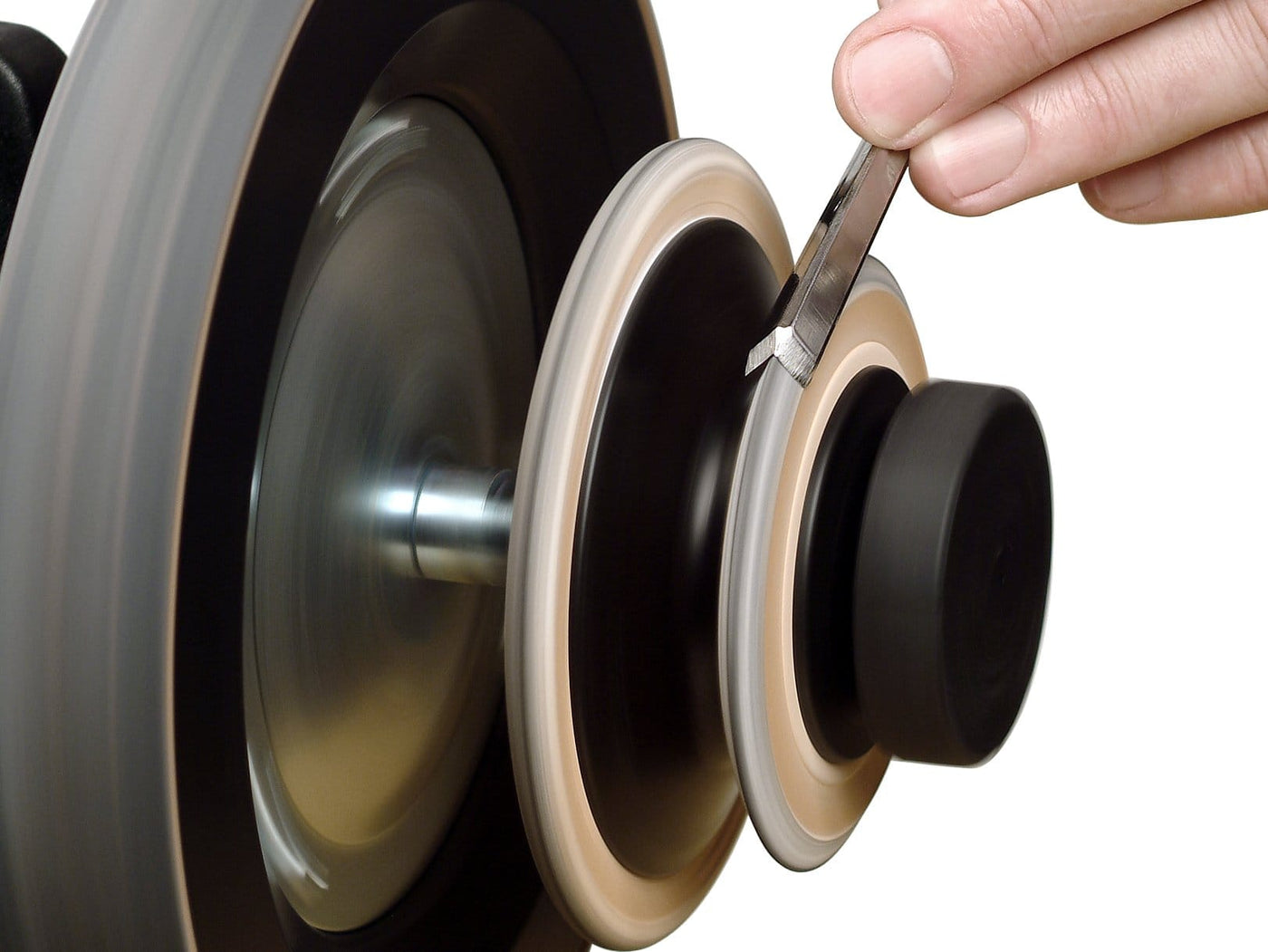 A person is sharpening a blade on a Tormek Profiled Honing Wheel by TOR, carefully holding the blade against the rotating abrasive surface with the precision one would use for turning gouges.