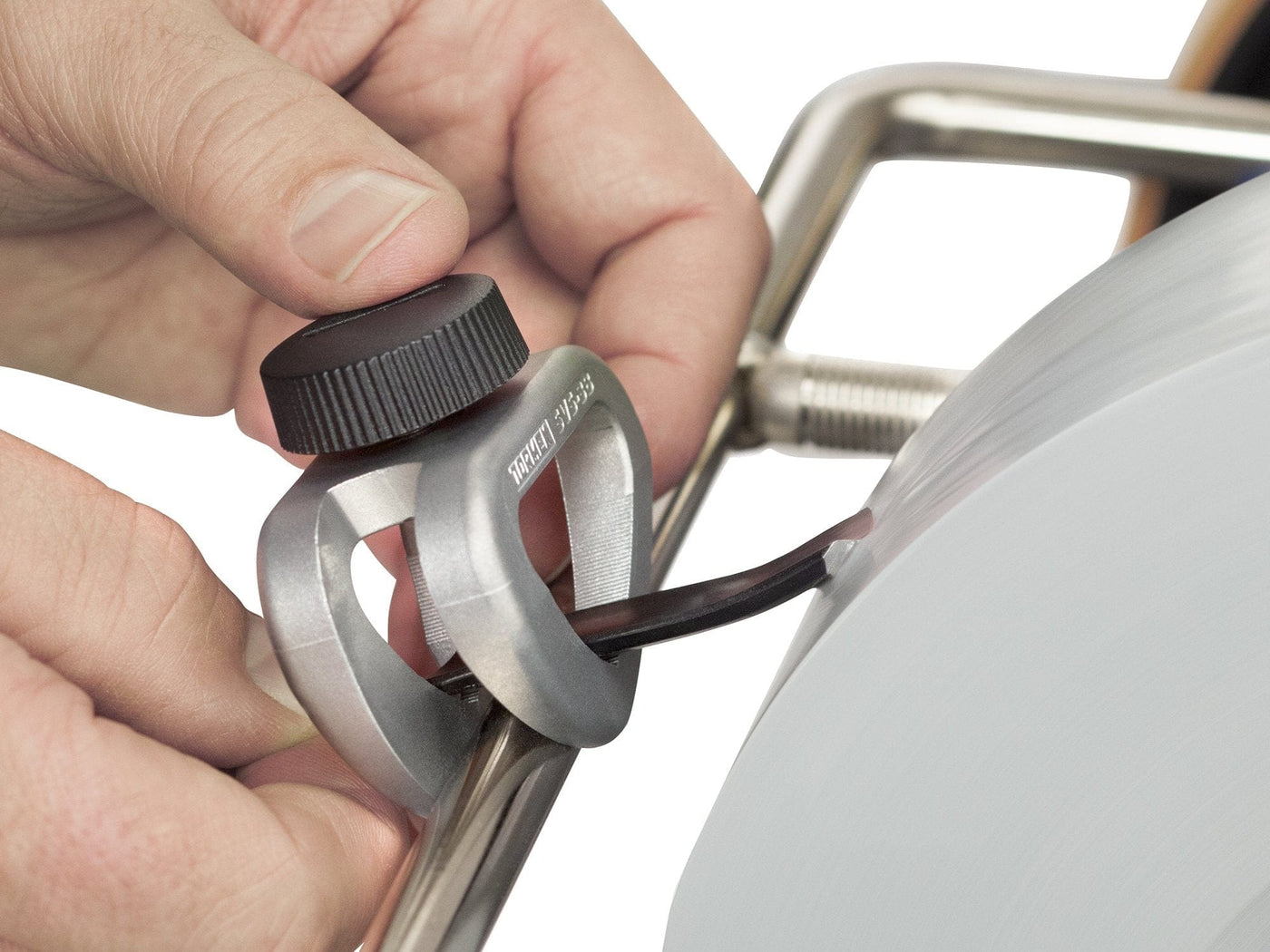 Close-up of a hand adjusting a black knob on the Tormek Short Tool Kit by TOR with a circular component, possibly indicating a calibration or tuning process for sharpening woodcarving tools.