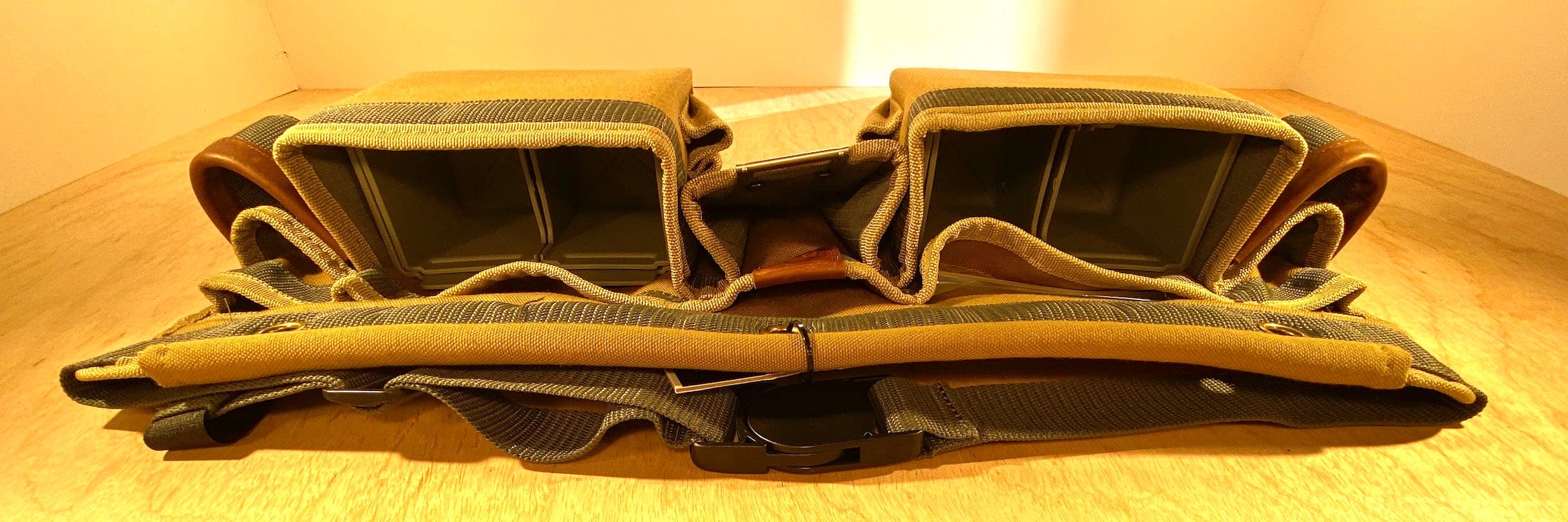 A pair of empty, padded storage compartments crafted from durable polyester canvas with straps, resting on a wooden surface, presumably part of the VET Veto Pro Pac TA-WBX Waist Apron With Boxed Pockets for efficient tool storage.